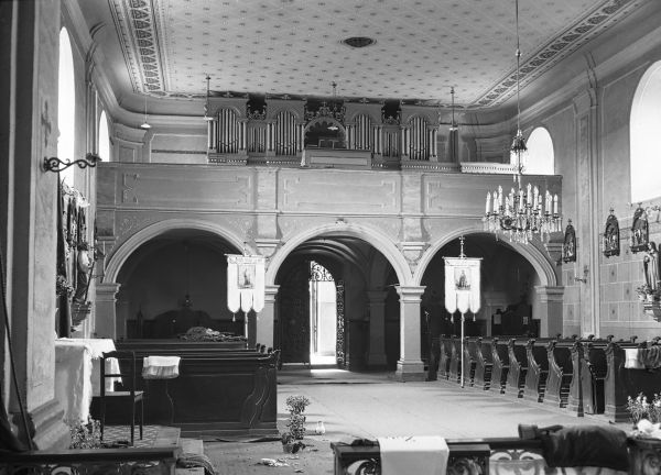 Pohled do lodi kostela na snímku z roku 1934. Patrná je pestrá výmalba, boční oltáře a varhany z roku 1907.